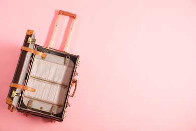 Photo of Open empty suitcase on pink background, top view. Space for text