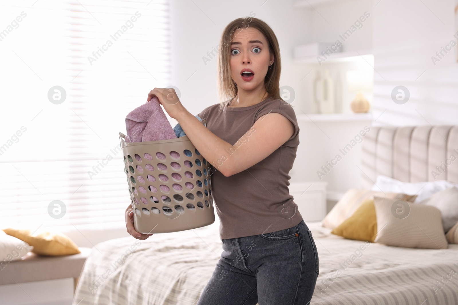 Photo of Emotional housewife with basket full of laundry at home