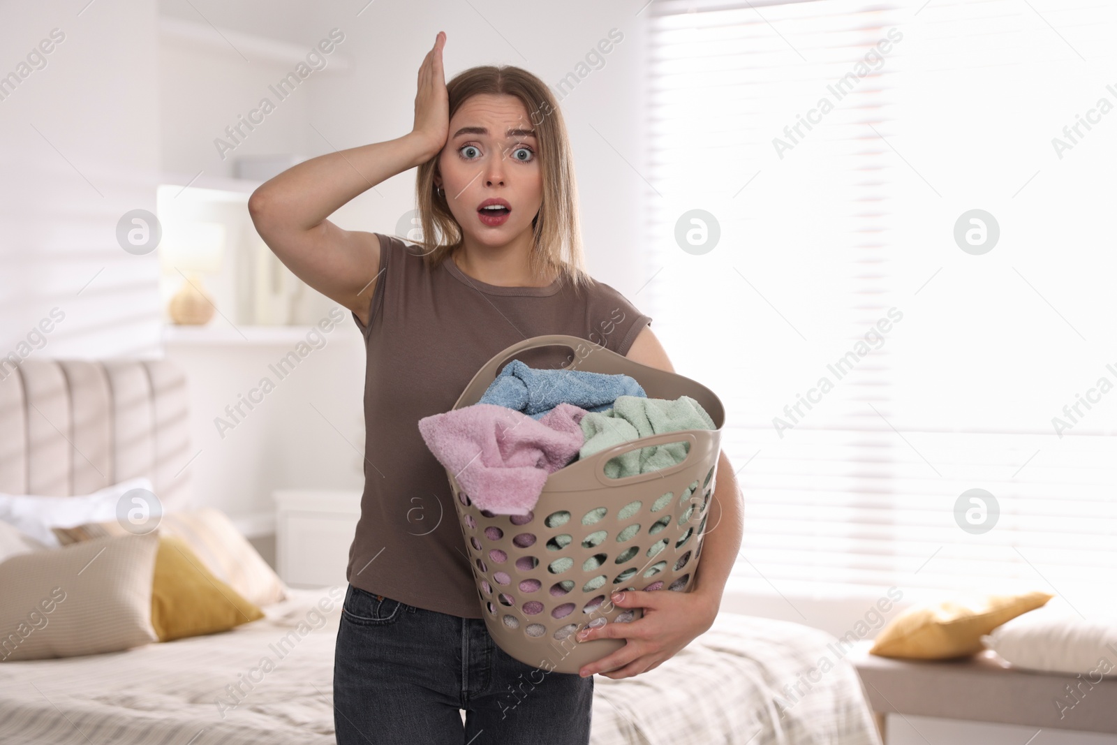 Photo of Emotional housewife with basket full of laundry at home