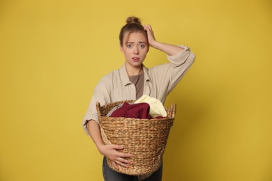 Tired housewife with basket full of laundry on yellow background