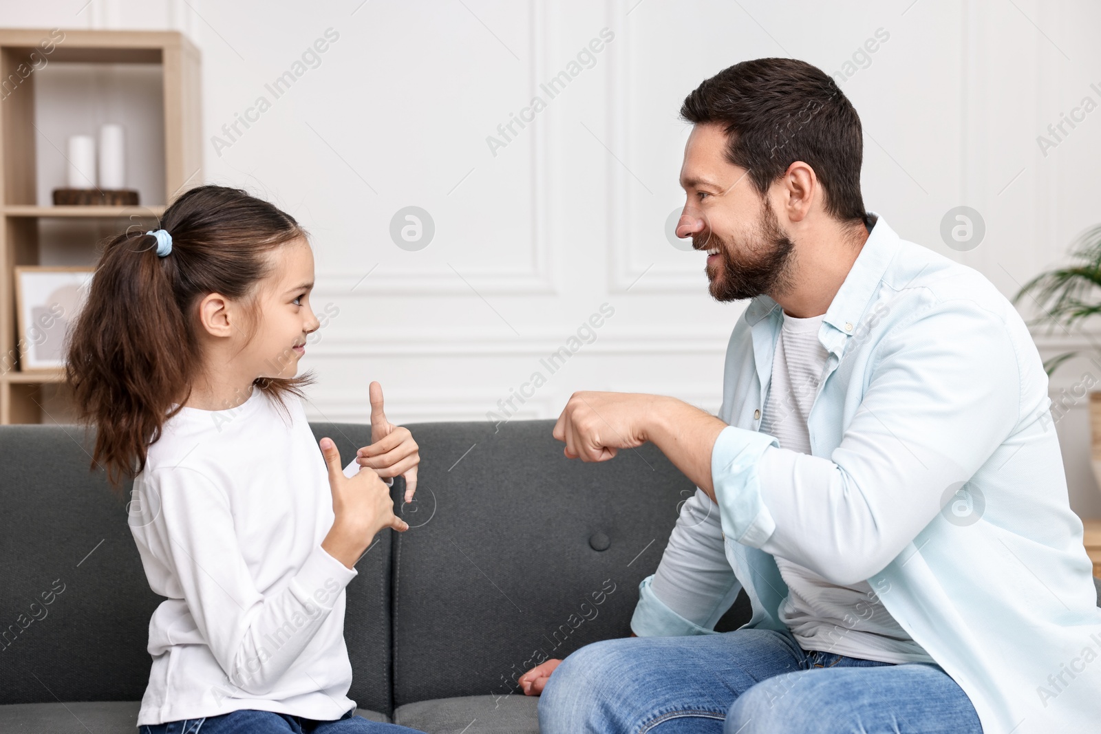 Photo of Man and his daughter using sign language for communication at home