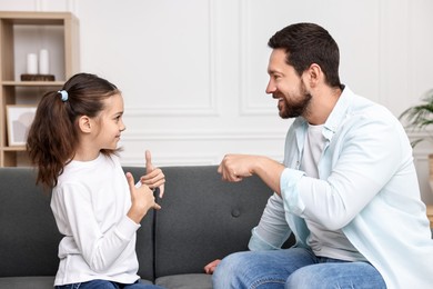 Photo of Man and his daughter using sign language for communication at home