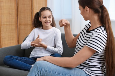 Photo of Woman and her daughter using sign language for communication at home