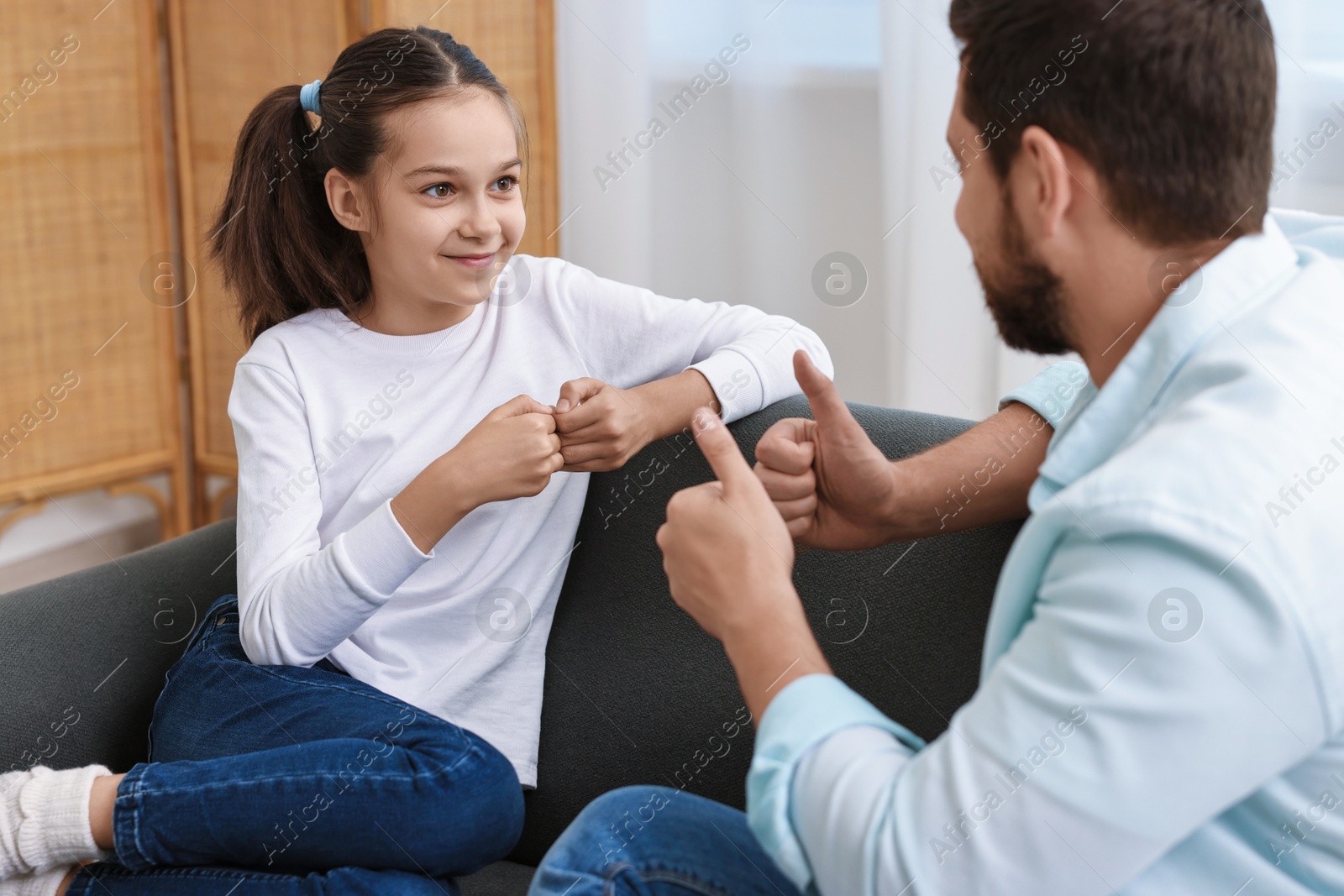 Photo of Man and his daughter using sign language for communication at home