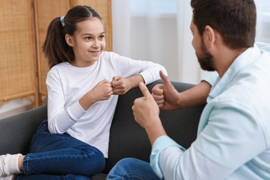 Photo of Man and his daughter using sign language for communication at home