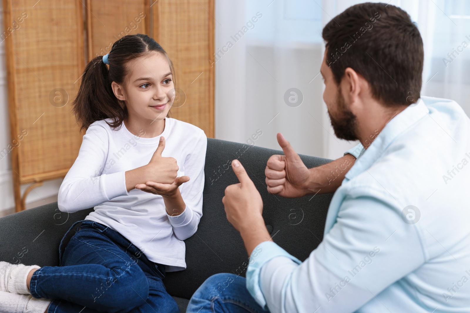 Photo of Man and his daughter using sign language for communication at home