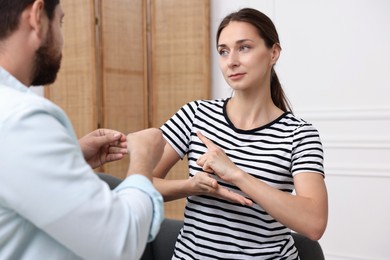 Photo of Man and woman using sign language for communication at home