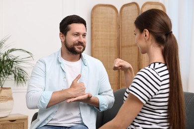 Photo of Man and woman using sign language for communication at home