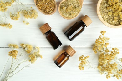 Photo of Tinctures in bottles and helichrysum flowers on white wooden table, flat lay