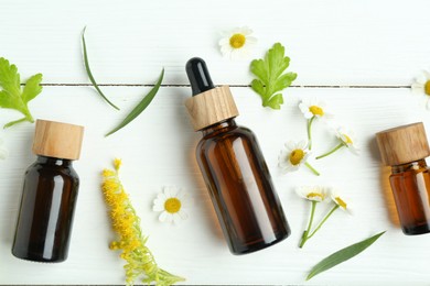 Photo of Tinctures in bottles, goldenrod flower and chamomiles on white wooden table, flat lay