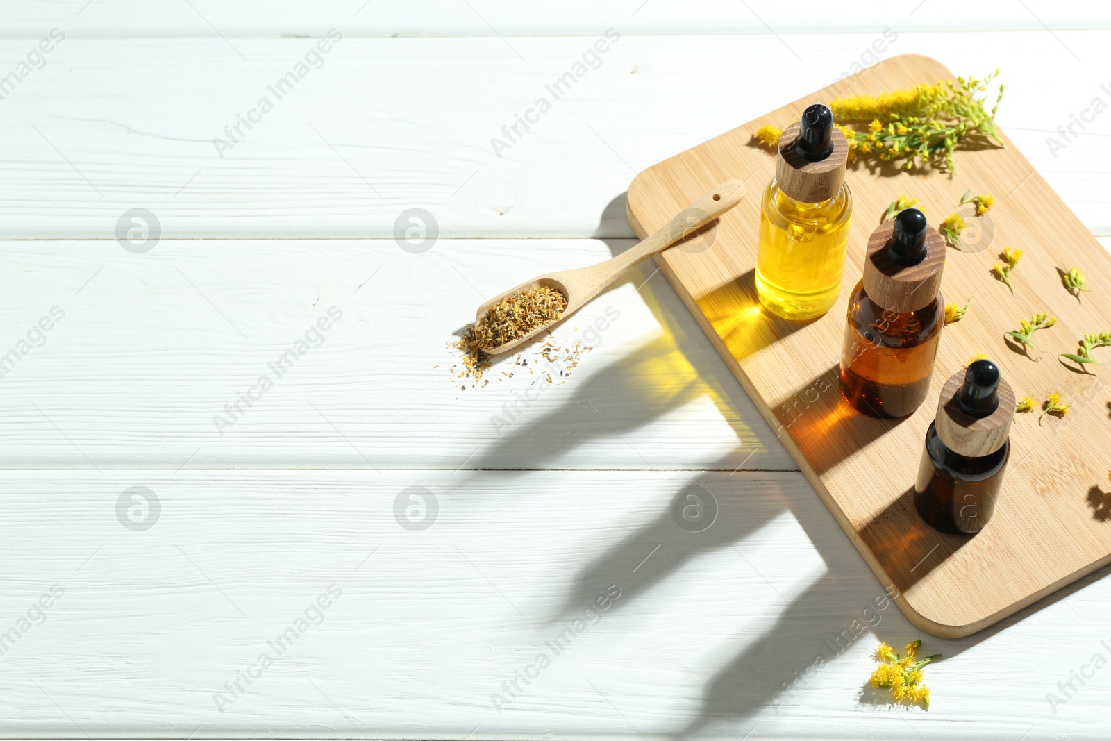 Photo of Tinctures in bottles and goldenrod flowers on white wooden table, space for text