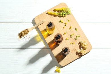 Photo of Tinctures in bottles, goldenrods and helichrysum flowers on white wooden table, top view