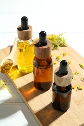 Photo of Tinctures in bottles and medicinal herbs on white wooden table