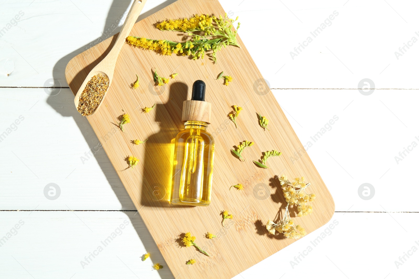 Photo of Tincture in bottle, goldenrods and helichrysum flowers on white wooden table, top view