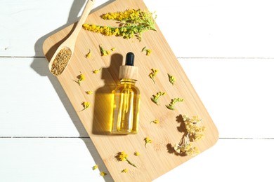 Photo of Tincture in bottle, goldenrods and helichrysum flowers on white wooden table, top view