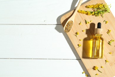 Photo of Tincture in bottle, goldenrods and helichrysum flowers on white wooden table, top view. Space for text