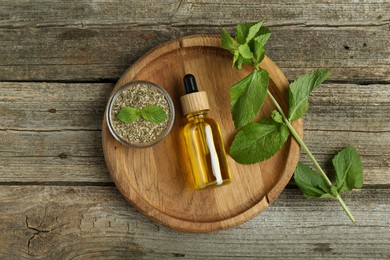 Photo of Tincture in bottle and herbs on wooden table, top view