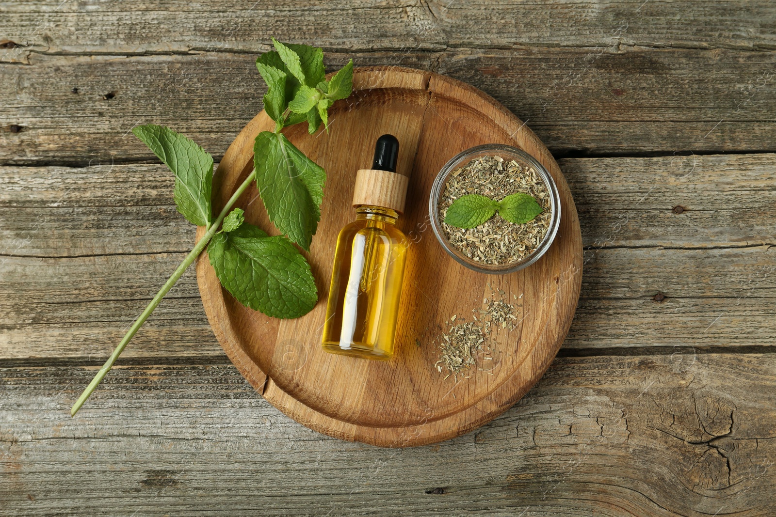 Photo of Tincture in bottle and herbs on wooden table, top view