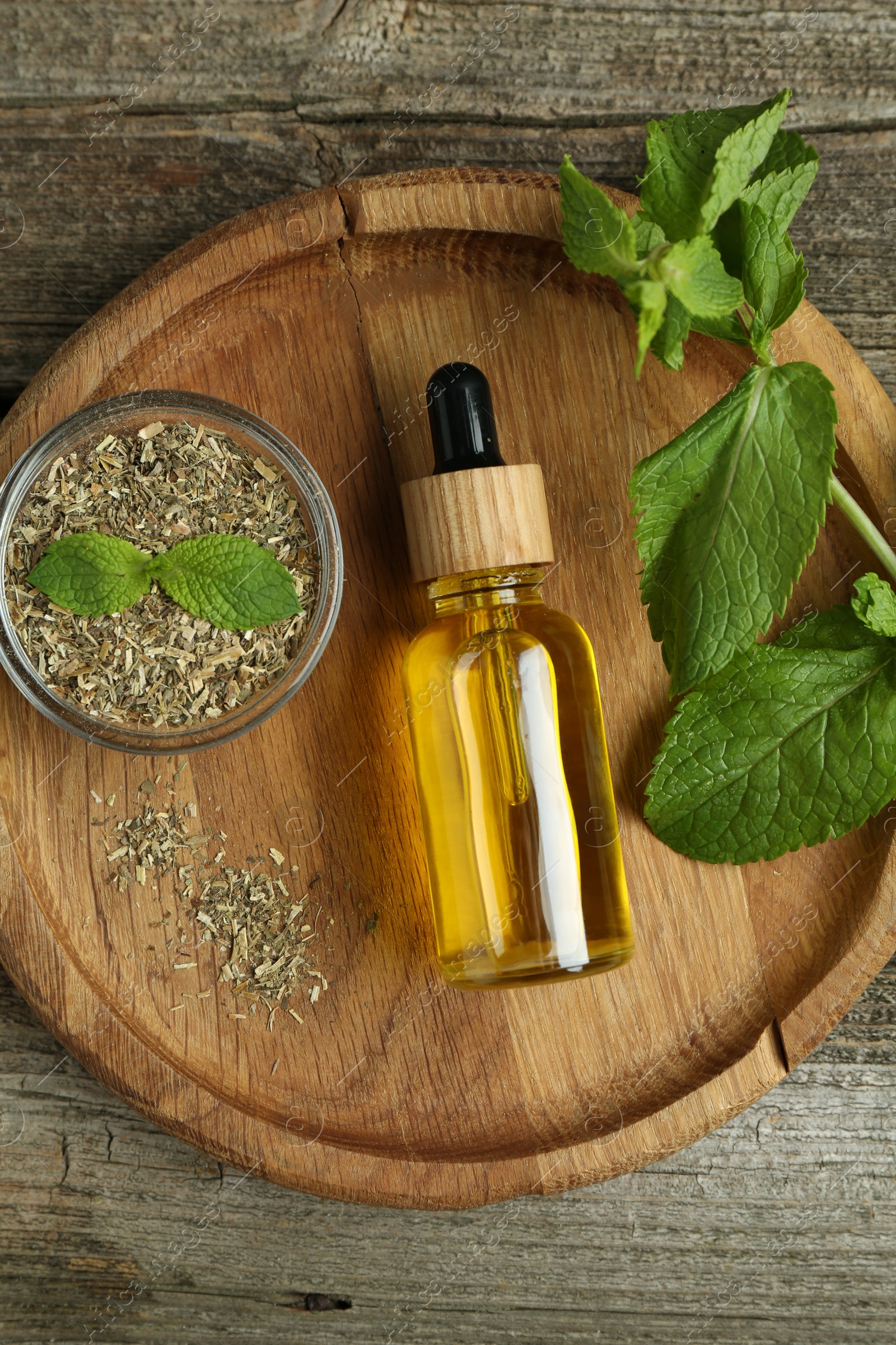 Photo of Tincture in bottle and herbs on wooden table, top view