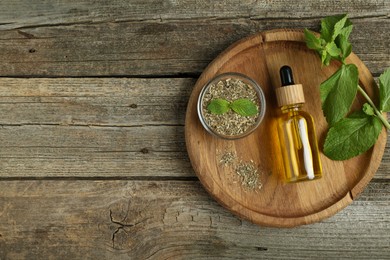 Photo of Tincture in bottle and herbs on wooden table, top view. Space for text