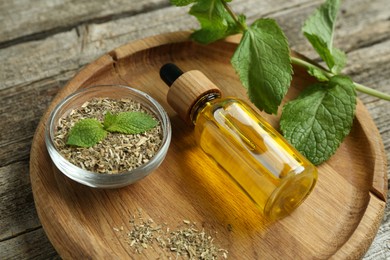 Photo of Tincture in bottle and herbs on wooden table, closeup