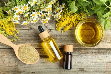 Photo of Tinctures and medicinal herbs on wooden table, flat lay