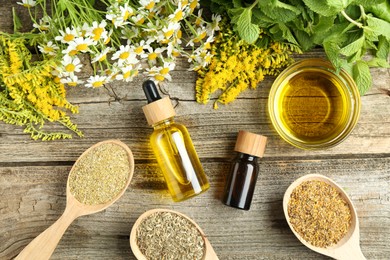 Photo of Tinctures and medicinal herbs on wooden table, flat lay