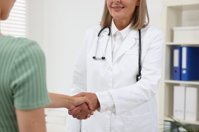 Photo of Senior doctor shaking hands with patient in hospital, closeup