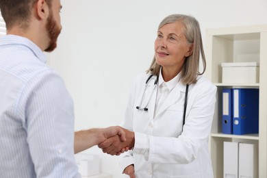 Senior doctor shaking hands with patient in hospital