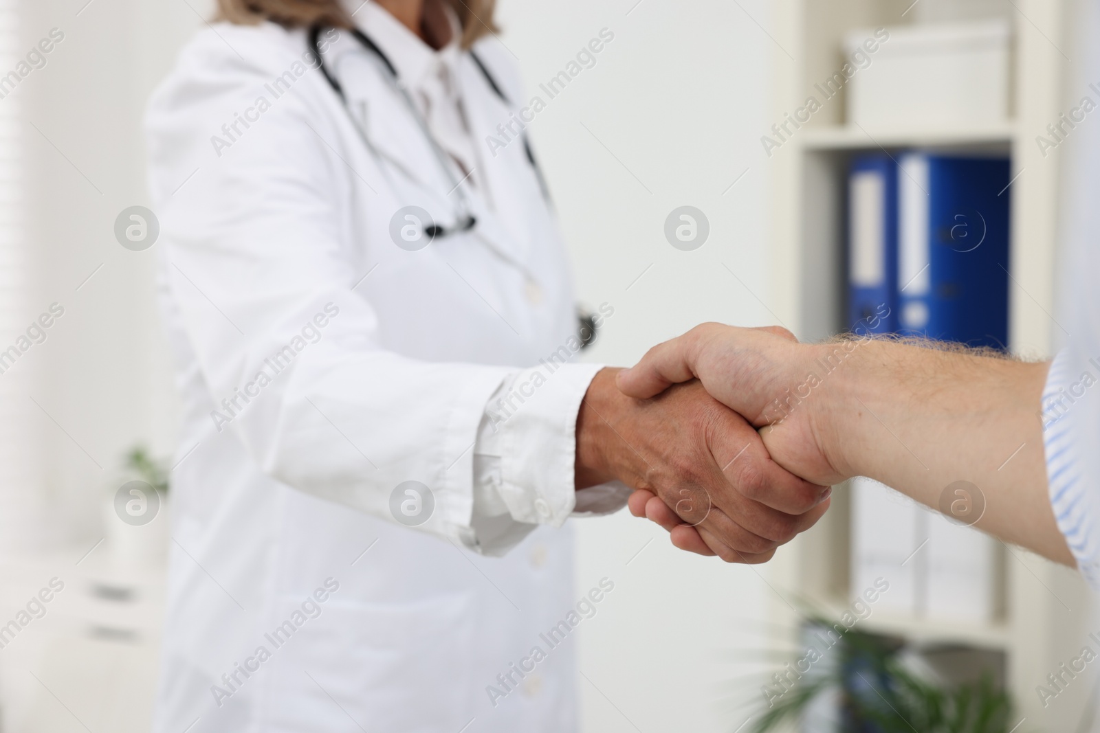 Photo of Senior doctor shaking hands with patient in hospital, closeup