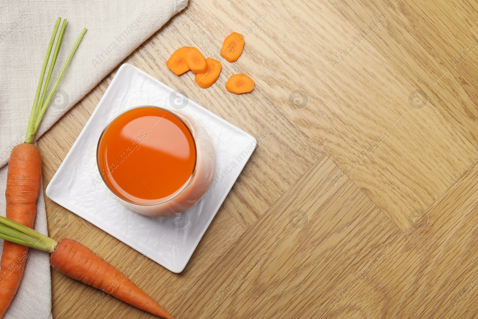 Photo of Healthy juice in glass and fresh carrot on wooden table, flat lay. Space for text