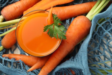 Healthy juice in glass and fresh carrot on table, top view