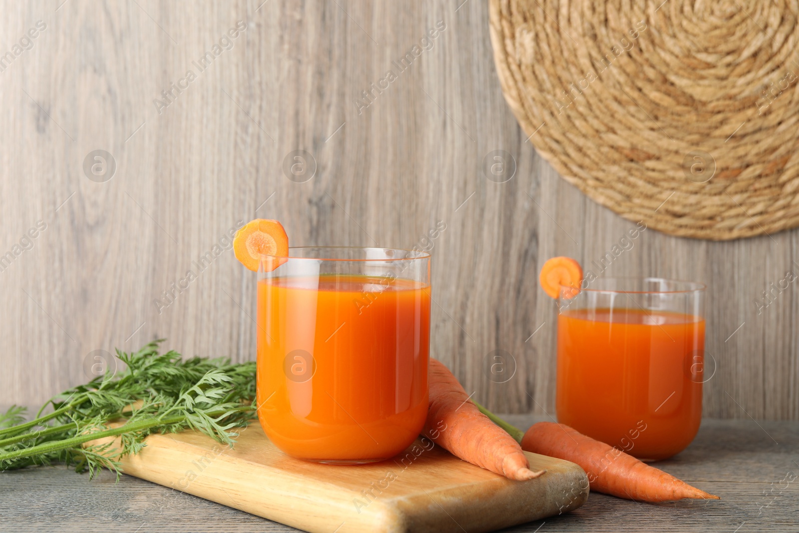 Photo of Healthy carrot juice in glasses and fresh vegetables on wooden table