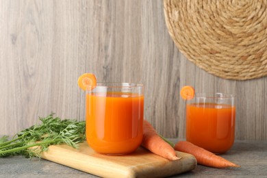 Photo of Healthy carrot juice in glasses and fresh vegetables on wooden table