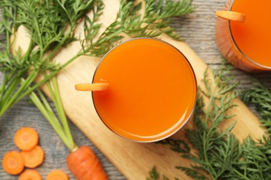 Photo of Healthy carrot juice in glasses and fresh vegetables on wooden table, top view