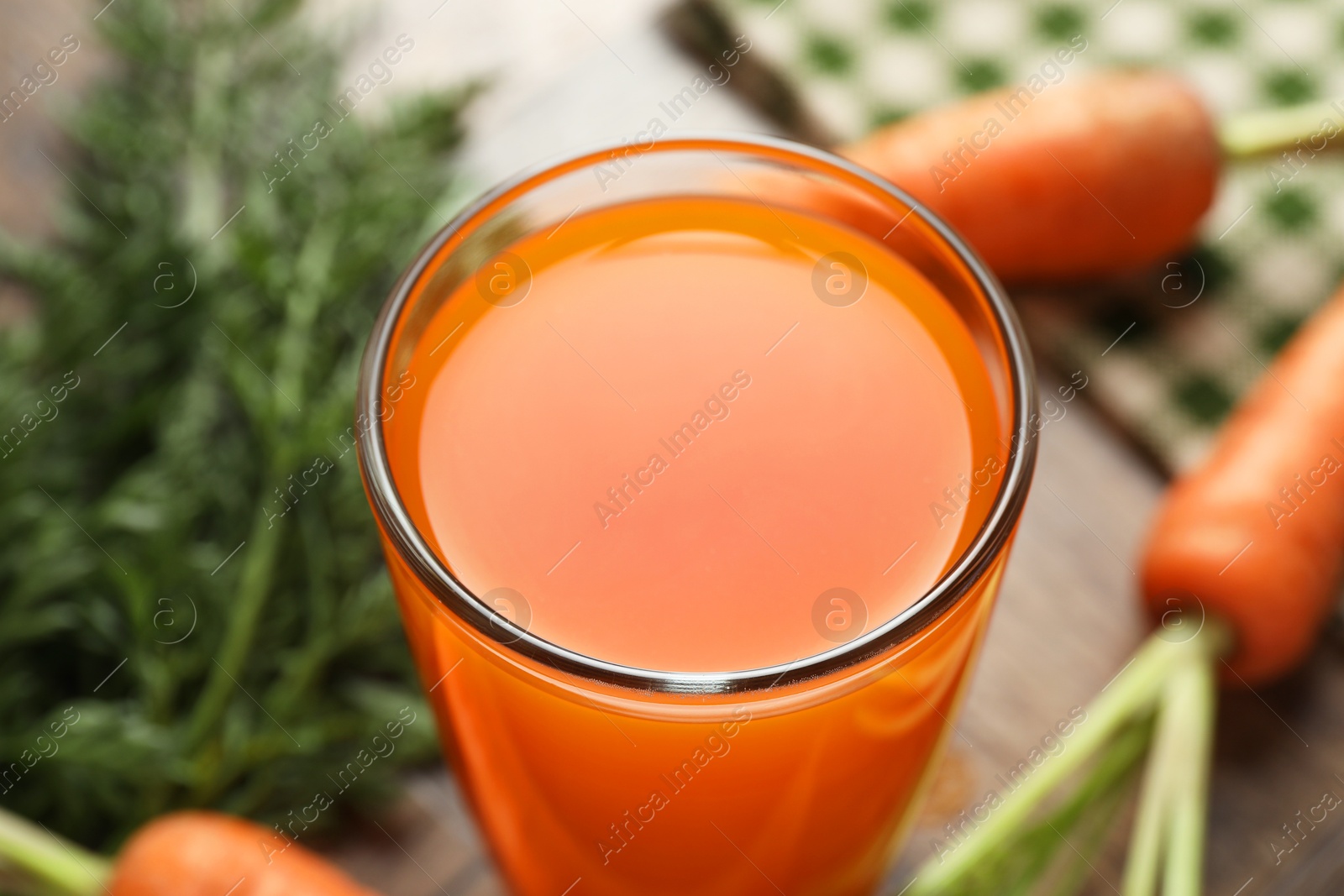 Photo of Healthy carrot juice in glass and fresh vegetables on table, closeup