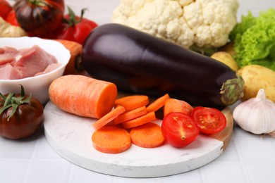 Photo of Different vegetables and raw meat for stew on white tiled table