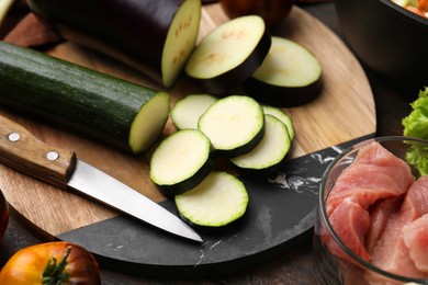 Photo of Cooking stew. Cut zucchini and eggplant on wooden table, closeup