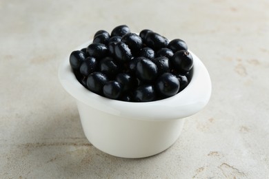 Ripe black currants in bowl on light table, closeup