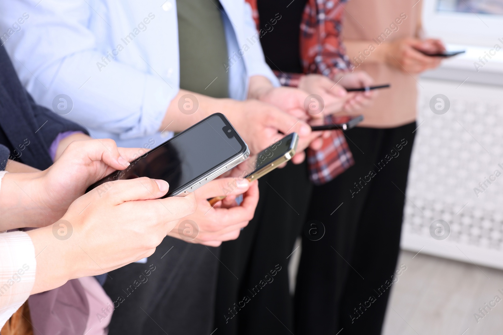 Photo of People holding smartphones with blank screens indoors, closeup