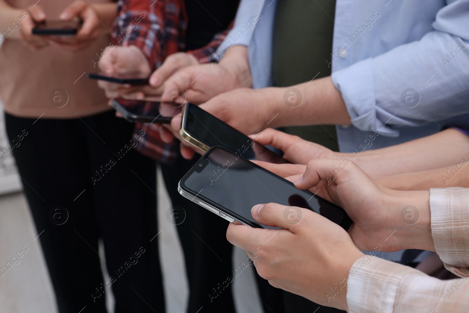 Photo of People holding smartphones with blank screens indoors, closeup