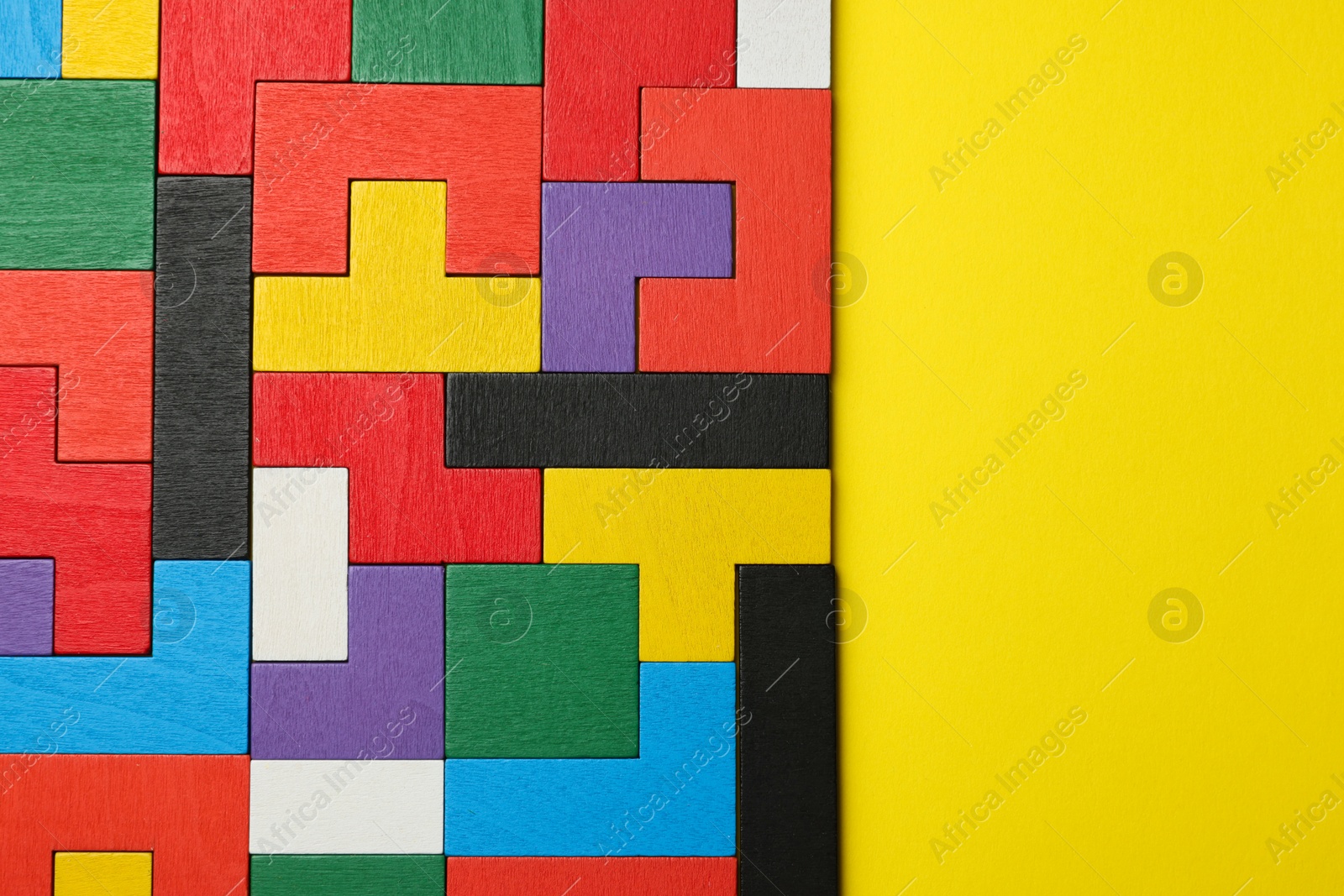 Photo of Colorful wooden puzzle pieces on yellow background, top view. Space for text