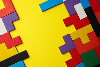 Photo of Colorful wooden puzzle pieces on yellow background, top view