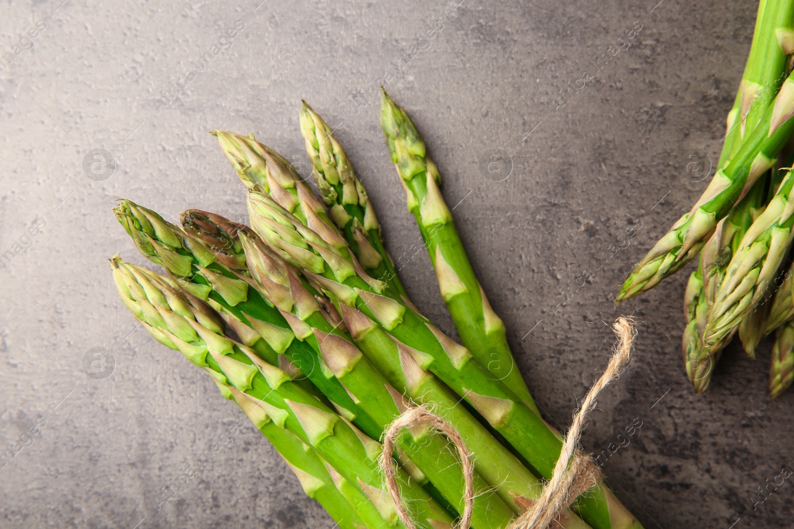 Photo of Fresh green asparagus stems on grey textured table, flat lay