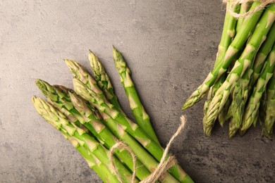 Fresh green asparagus stems on grey textured table, flat lay