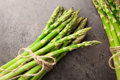 Fresh green asparagus stems on grey textured table, flat lay