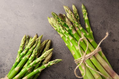 Fresh green asparagus stems on grey textured table, flat lay