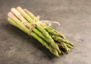 Bunch of fresh green asparagus stems on grey textured table, closeup