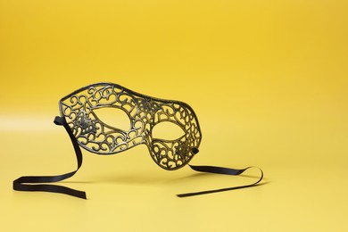 Photo of Beautiful carnival mask in air on yellow background