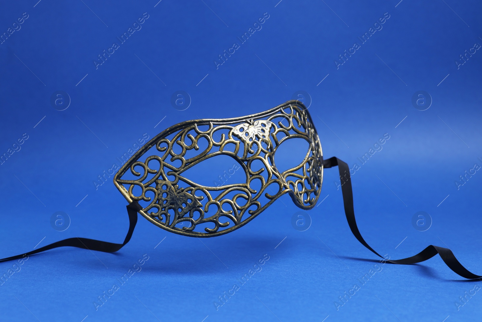 Photo of Beautiful carnival mask in air on blue background